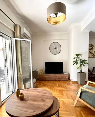 a living room with a table and a tv at Bright 2 bdr Pagrati apartment in Athens