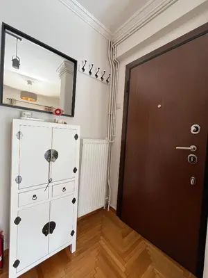 a white dresser with a mirror next to a door at Bright 2 bdr Pagrati apartment in Athens