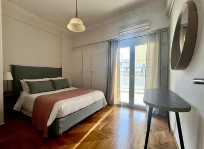 a bedroom with a bed and a table and a window at Bright 2 bdr Pagrati apartment in Athens