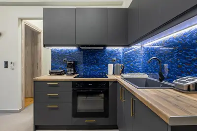 a kitchen with black appliances and blue tiles at Cesily 2-Bedroom Apartment in Athens in Athens
