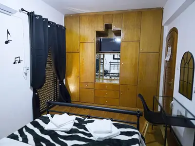 a bedroom with a bed and a cabinet with a television at Nicko’s room in Piraeus