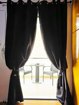 a window with black curtains in a room with a table at Nicko’s room in Piraeus