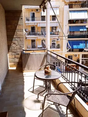 a table and chairs on a balcony with a building at Nicko’s room in Piraeus