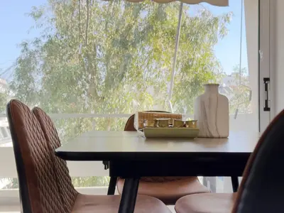 a table with chairs and a vase on it with a window at Kanari Sea View 55sqm apt in Alimos in Athens