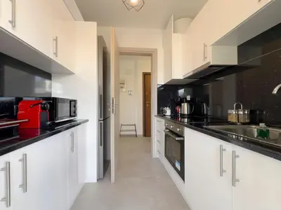 a kitchen with white cabinets and black counter tops at Kanari Sea View 55sqm apt in Alimos in Athens