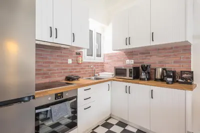 a kitchen with white cabinets and a brick wall at Quiet Embassy Suite by CloudKeys in Athens