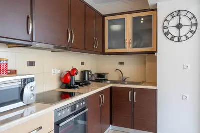 a kitchen with wooden cabinets and a clock on the wall at Comfort 1BR apt with amazing balcony at Piraeus in Piraeus