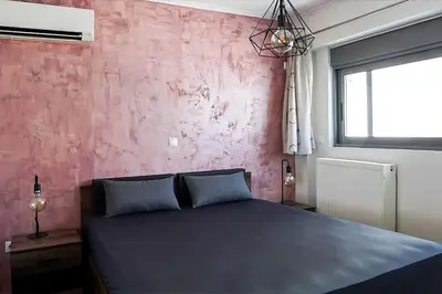 a bedroom with a black bed and a pink wall at Comfort 1BR apt with amazing balcony at Piraeus in Piraeus