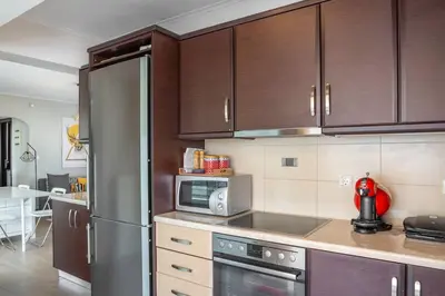 a kitchen with wooden cabinets and a stainless steel refrigerator at Comfort 1BR apt with amazing balcony at Piraeus in Piraeus
