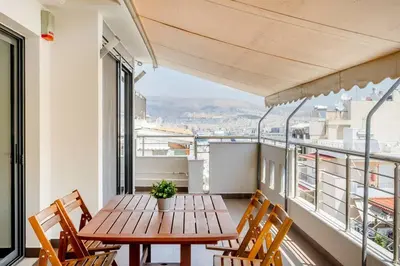 a balcony with a wooden table and chairs at Comfort 1BR apt with amazing balcony at Piraeus in Piraeus
