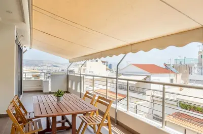 a balcony with a wooden table and chairs and a view at Comfort 1BR apt with amazing balcony at Piraeus in Piraeus
