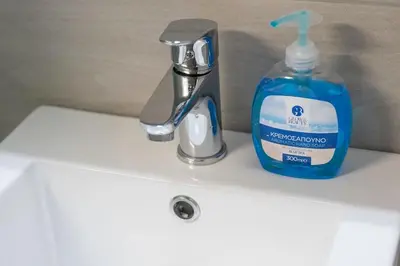 a bottle of soap sitting next to a bathroom sink at New and renovated studio close to Megaro Mousikis in Athens