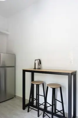 a table with two stools next to a refrigerator at New and renovated studio close to Megaro Mousikis in Athens