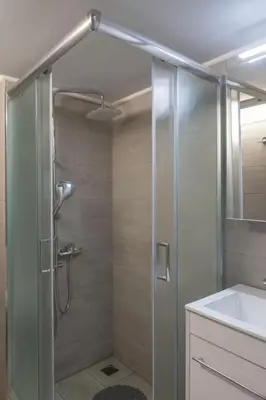 a shower with a glass door next to a sink at New and renovated studio close to Megaro Mousikis in Athens