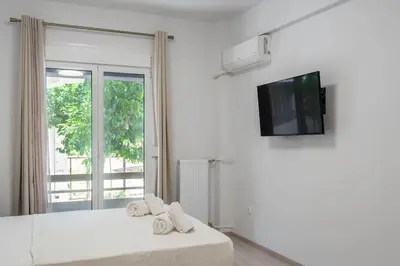 a white bedroom with a bed and a tv at New and renovated studio close to Megaro Mousikis in Athens
