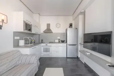 a white kitchen with a refrigerator and a sink at Penthouse with views close to Monastiraki metro in Athens