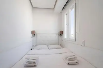 two beds in a white room with a window at Penthouse with views close to Monastiraki metro in Athens