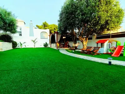 a yard with a green lawn with chairs and a house at Rsquared (Riviera Residence) in Aghia Marina
