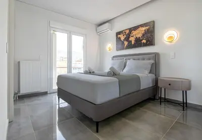 a white bedroom with a large bed and a window at Two Bedroom Sea View Apartment in Glyfada Beach in Athens