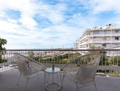 a balcony with two chairs and a table and a building at Two Bedroom Sea View Apartment in Glyfada Beach in Athens