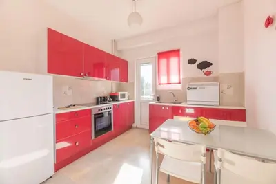 a red kitchen with white appliances and red cabinets at The HostMaster Beachside Retreat in Vari