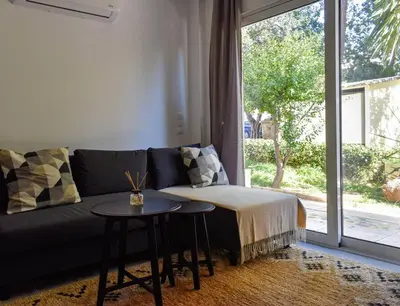a living room with a couch and a table and a window at Glyfada Maisonette by Taurus in Athens