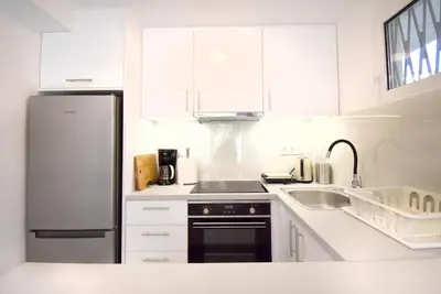 a white kitchen with a refrigerator and a sink at Glyfada Maisonette by Taurus in Athens