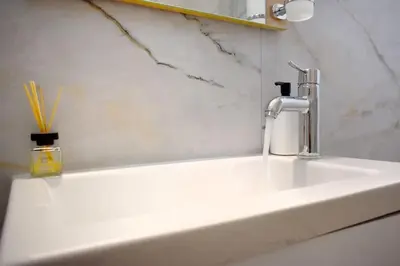 a white sink with a faucet and a mirror at Glyfada Maisonette by Taurus in Athens