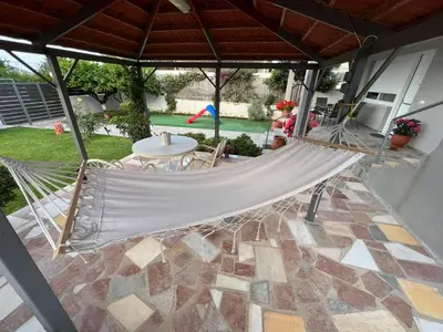 a hammock on a patio with a table at Seaside Luxury Apartments in Porto Rafti