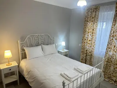 a bedroom with a white bed with two tables and a window at Seaside Luxury Apartments in Porto Rafti