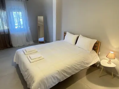 a bedroom with a large white bed with a lamp at Seaside Luxury Apartments in Porto Rafti
