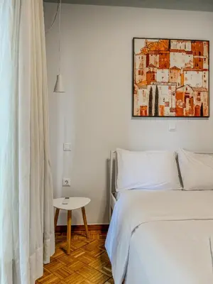 a white bedroom with a bed and a table at Apartment near Metro + Port in Piraeus