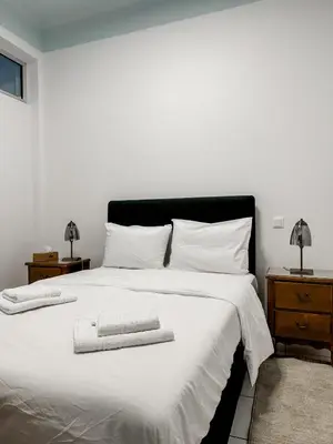 a bedroom with a white bed with two towels on it at Apartment near Metro + Port in Piraeus