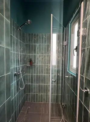 a green tiled bathroom with a shower with a glass door at Apartment near Metro + Port in Piraeus