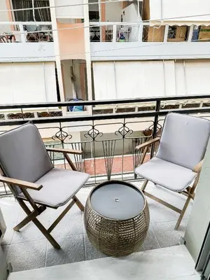 two chairs and a coffee table on a balcony at Apartment near Metro + Port in Piraeus
