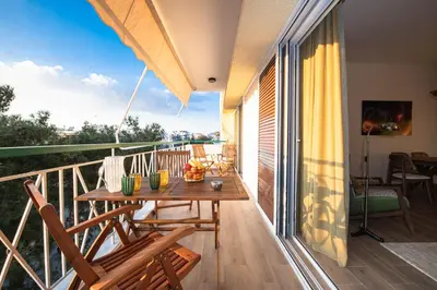 a balcony with a wooden table and chairs at Artsy Spacious Cozy Apartment in Glyfada Center in Athens