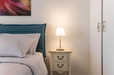a bedroom with a bed and a lamp on a night stand at Artsy Spacious Cozy Apartment in Glyfada Center in Athens
