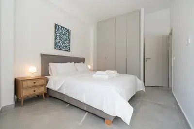 a bedroom with a large white bed and a night stand at Athenian Gem, Fully Renovated 2 Bedroom Apartment Near Acropolis in Athens