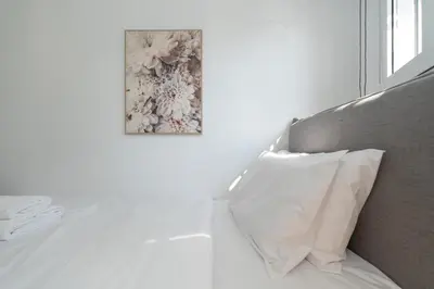 a bed with a pillow and a picture on the wall at Athenian Gem, Fully Renovated 2 Bedroom Apartment Near Acropolis in Athens