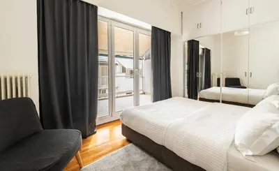 a bedroom with a bed and a chair and a window at YestayHomes Two Bedroom Apartment Tsakalof in Athens
