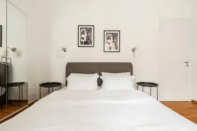 a bedroom with a white bed with two black stools at YestayHomes Two Bedroom Apartment Tsakalof in Athens
