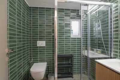 a green tiled bathroom with a toilet and a sink at The Urban Utopia at Glyfada in Athens