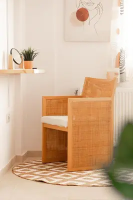 a wicker desk and chair in a room with a rug at Σπίτι με πισίνα δίπλα στο αεροδρόμιο. in Spáta