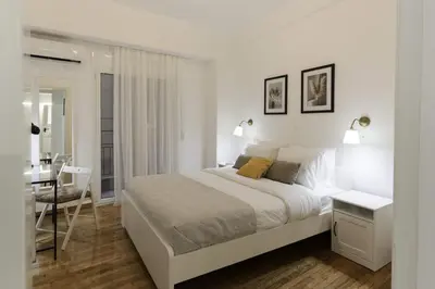 a white bedroom with a large bed and a desk at Phaedrus Living: City Center Koukaki Flat in Athens