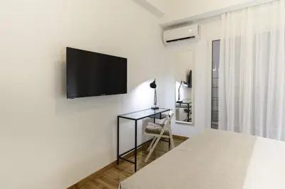 a bedroom with a desk and a tv on a wall at Phaedrus Living: City Center Koukaki Flat in Athens