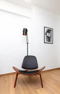a black chair in an empty room with a lamp at Apartment near City Center in Athens