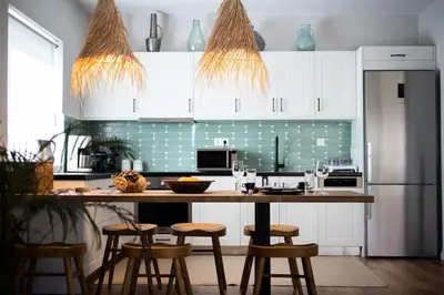 a kitchen with white cabinets and a counter with stools at HeyDay Living South 8 in Athens