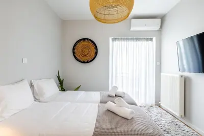a white bedroom with a large bed with two white towels at HeyDay Living South 8 in Athens