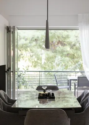 a dining room table with chairs and a large window at Vouliagmeni Stylish Apartment in Athens