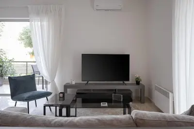 a living room with a couch and a tv at Vouliagmeni Stylish Apartment in Athens